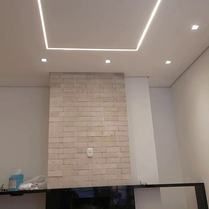 Parede revestida em pedra com sanca iluminada no teto